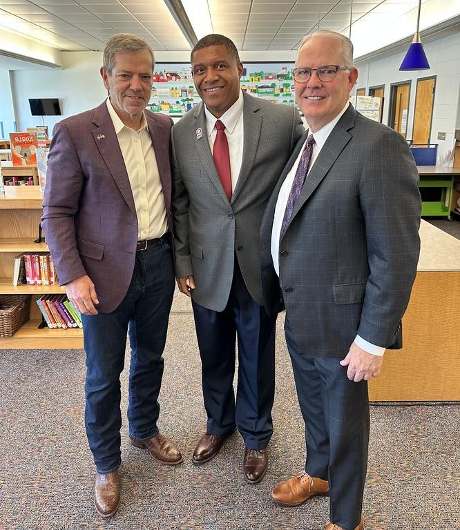 Three adults posing in school library